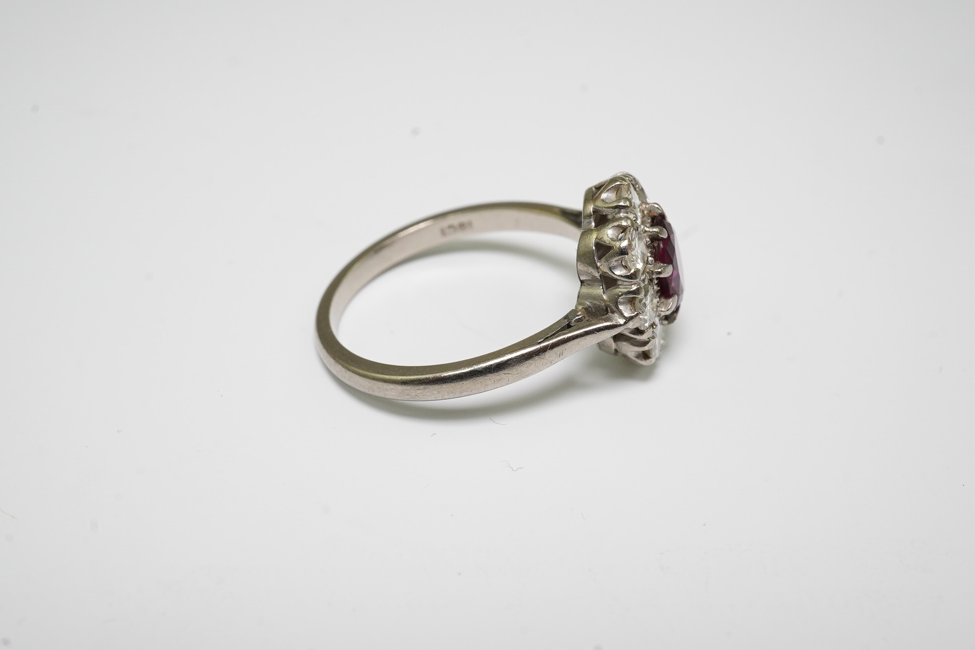 An 18ct white gold, ruby and diamond set oval cluster ring